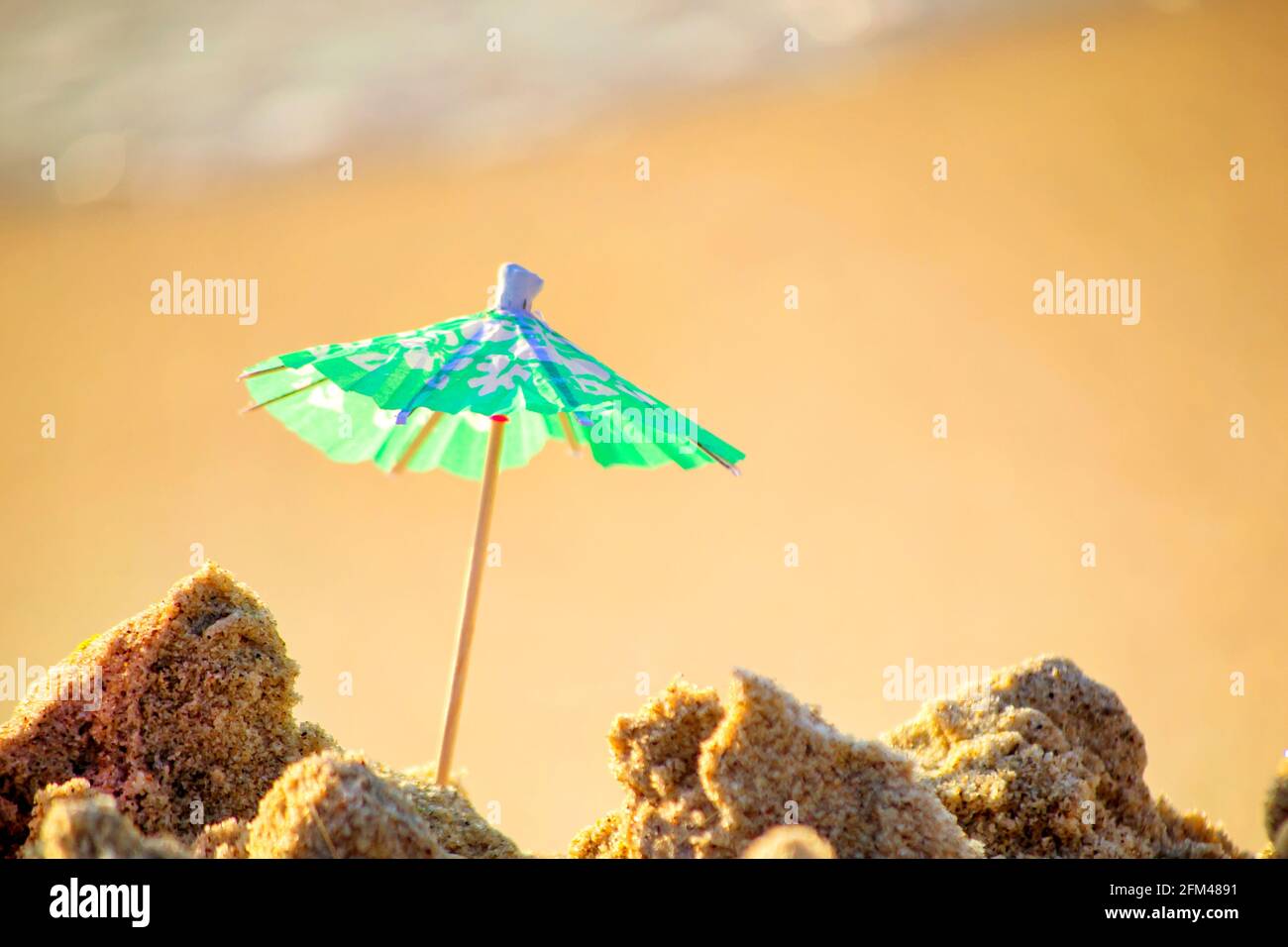Piccolo ombrellone in carta per cocktail stand in sabbia su sabbia Foto Stock