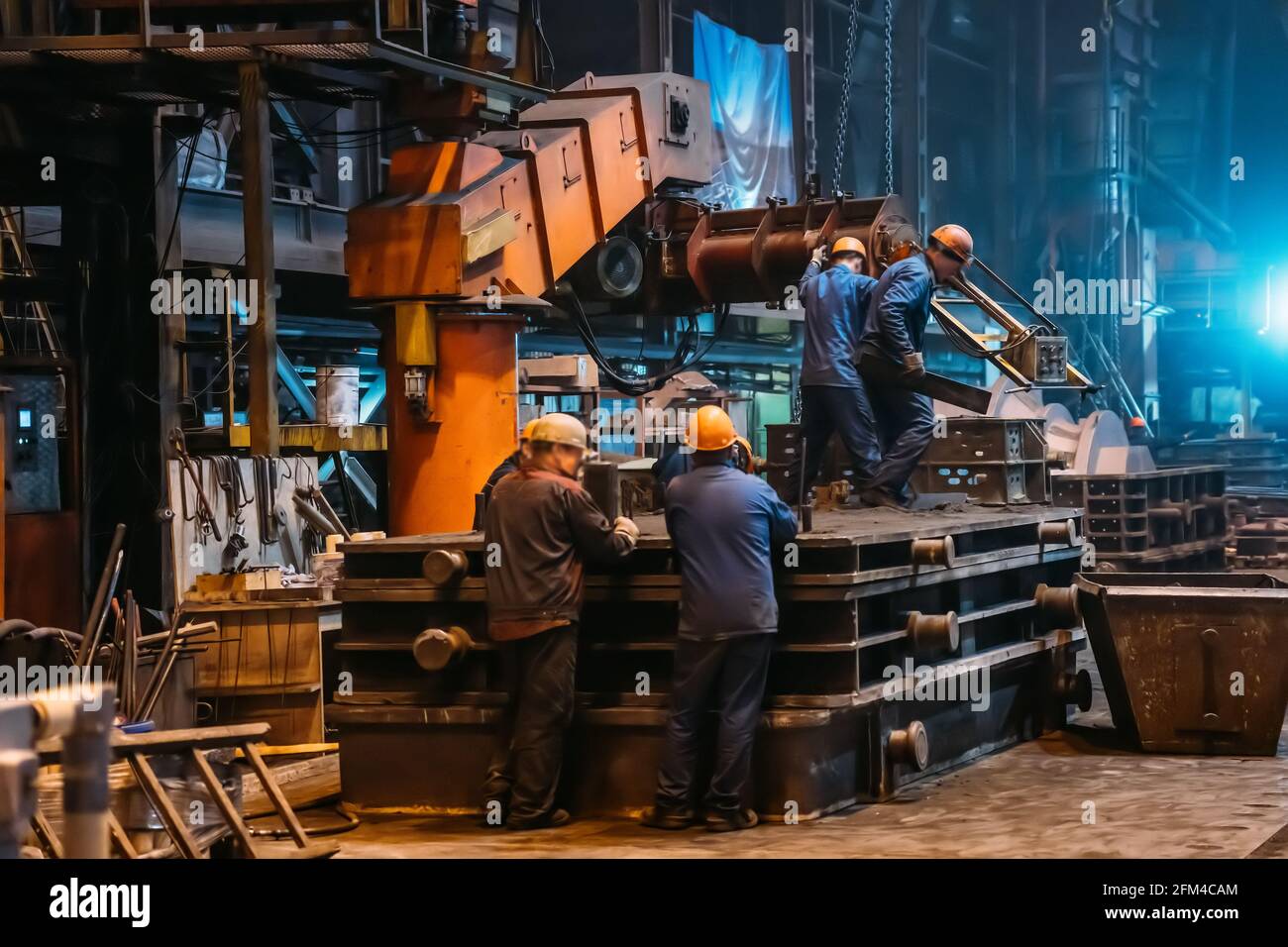 Lavoratori in corso di lavoro con grandi stampi di ghisa su fonderia di acciaieria. Foto Stock