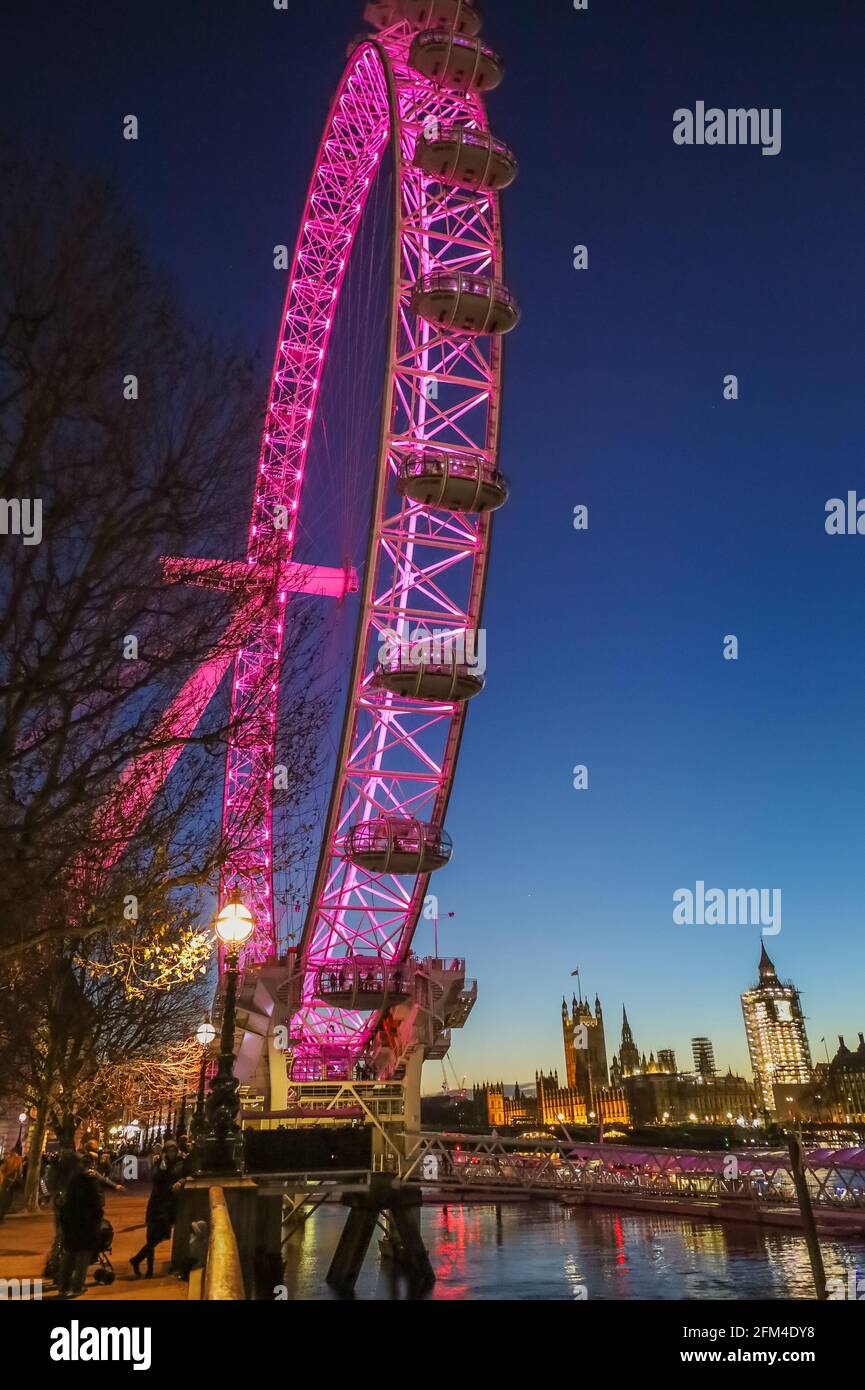 Il London Eye si è illuminato in rosso di notte con Big ben sullo sfondo Foto Stock