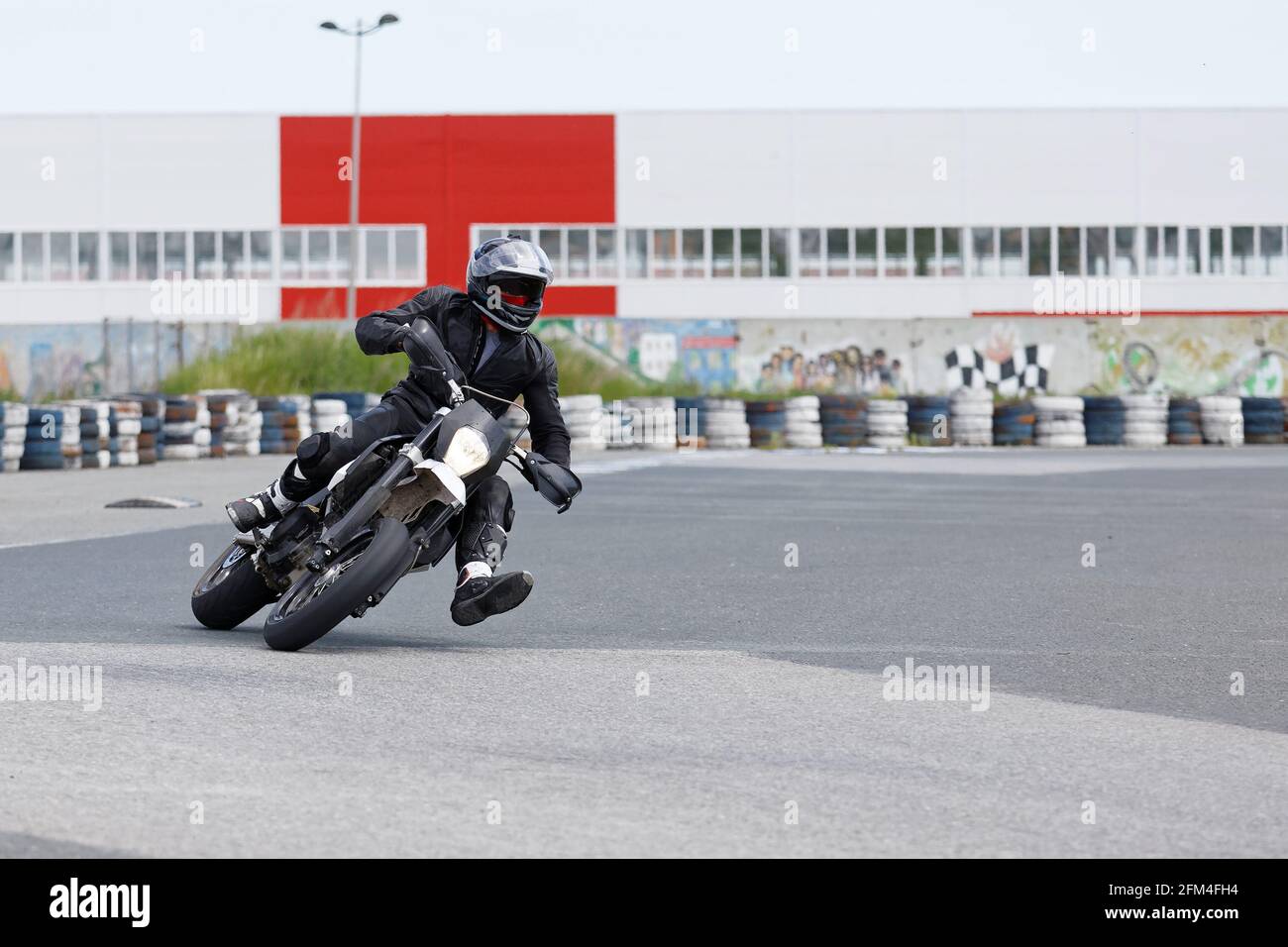 Ulyanovsk, Russia - 10 giugno 2017. Motociclista in uniforme nera che si inclina in una curva veloce in pista Foto Stock