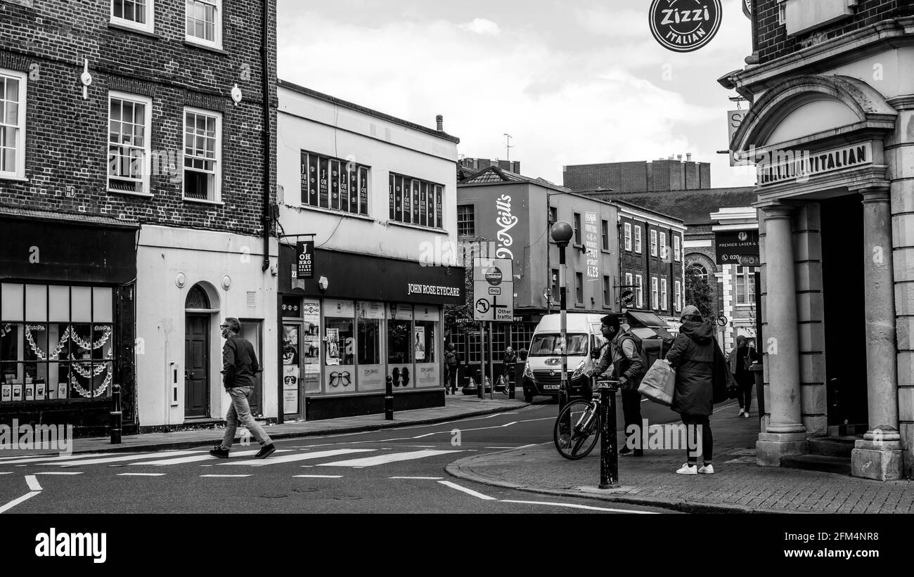 Kingston upon Thames London UK, maggio 04 2021, immagine bianca e nera uomo singolo utilizzando UN pedone o Zebra Crossing per attraversare la strada Foto Stock