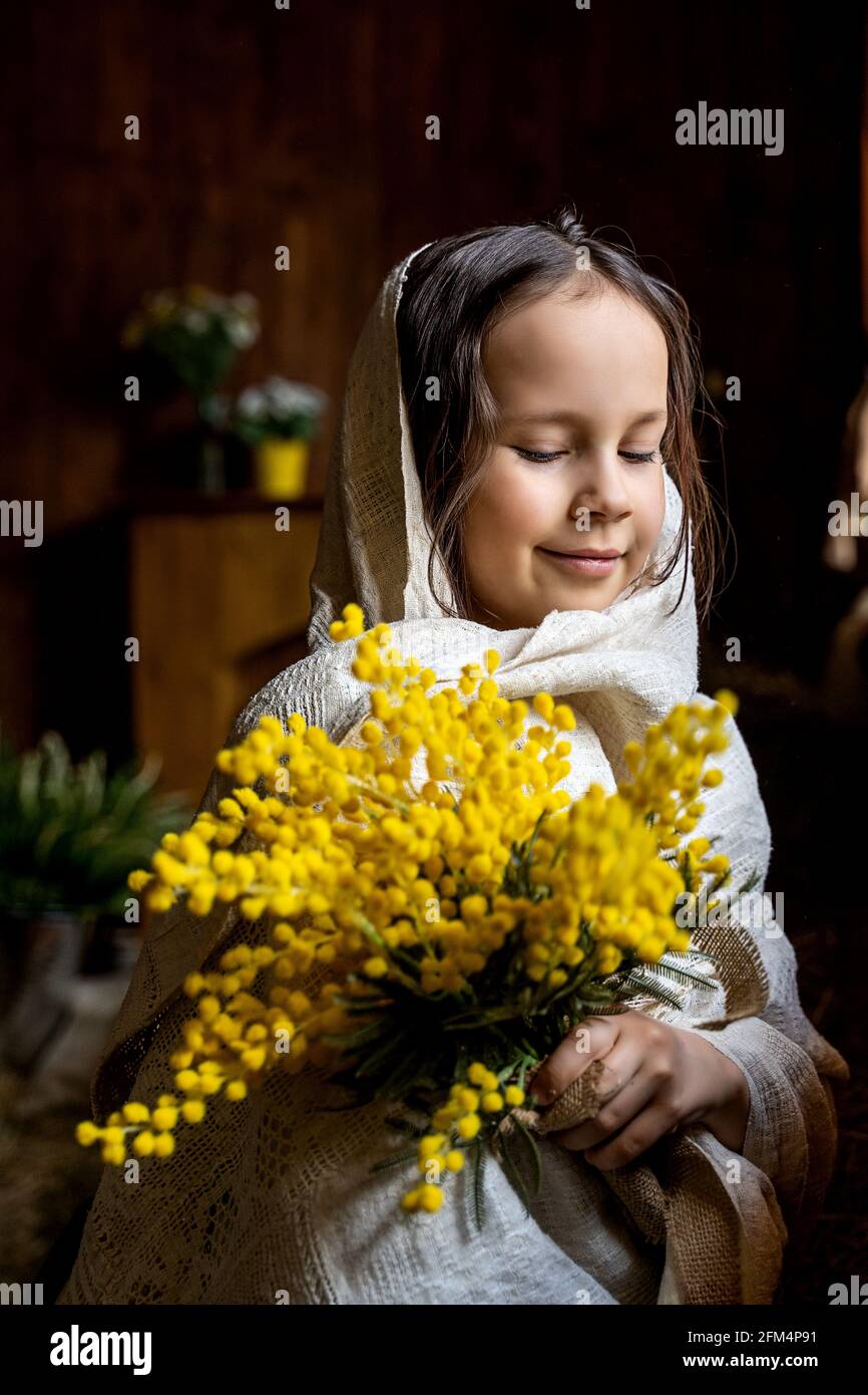 una bambina in un fazzoletto con una mimosa Foto stock - Alamy