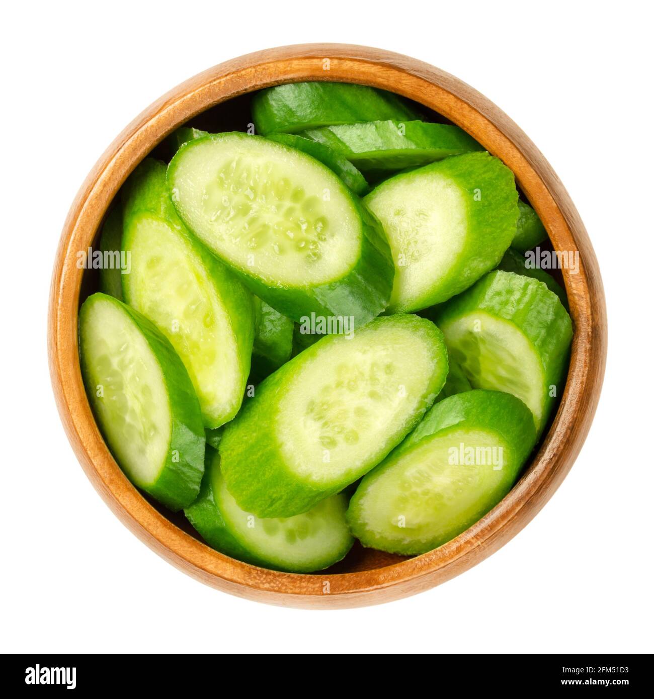 Fette di cetrioli di snack, in una ciotola di legno. Cumulo di cetrioli freschi, piccoli, giovani e interi tagliati diagonalmente. Cucumis sativus, una verdura. Foto Stock