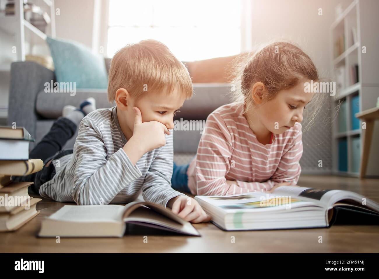 Carino bambini che si stendono sul pavimento e leggere libri Foto Stock