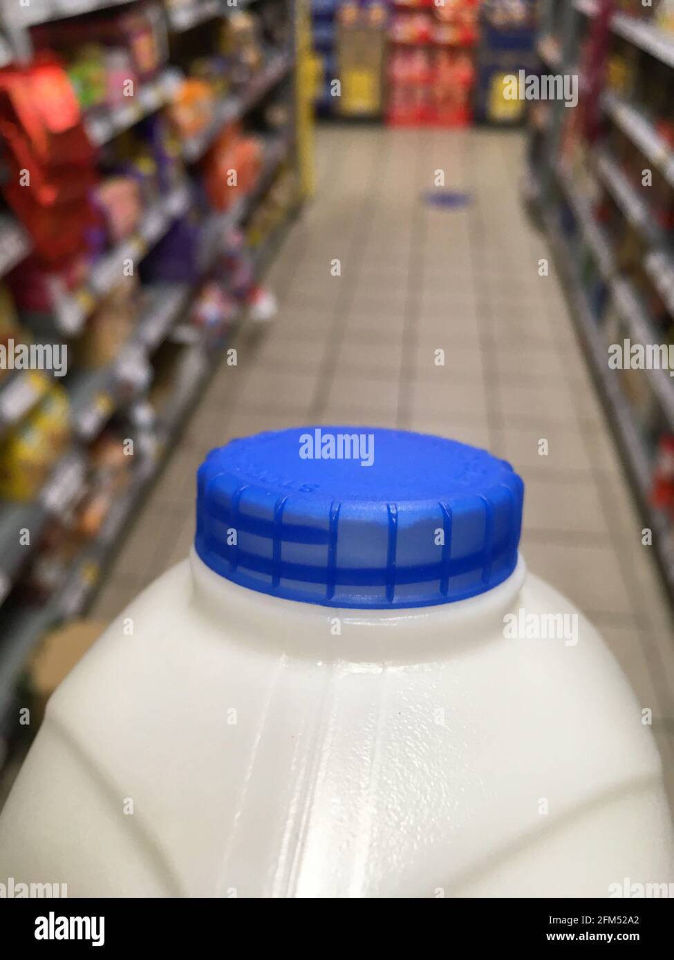 Una scatola di latte pastorizzato intero di grasso britannico con una parte superiore blu della bottiglia che viene trasportata da un ripiano alla cassa in un supermercato. Il cliente sta acquistando il latte dal negozio. REGNO UNITO. (123) Foto Stock