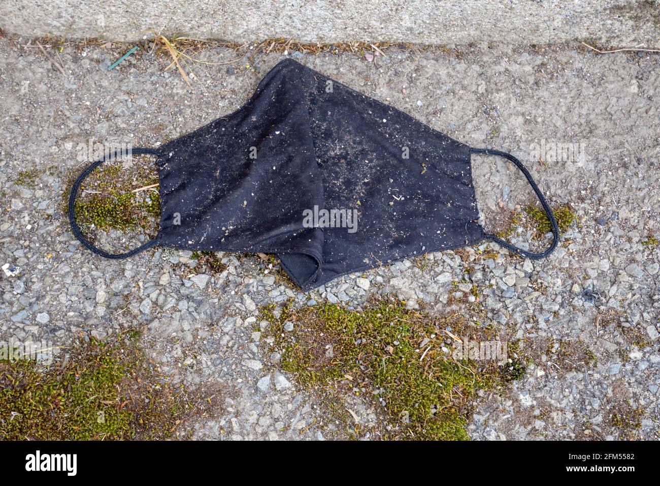 Maschera di tessuto nero gettata in strada. Foto Stock