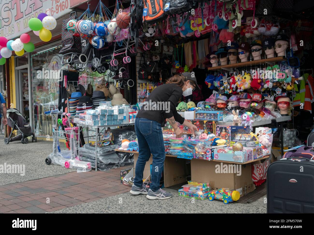 Una donna che vende giocattoli e knick knacks di fronte a un negozio di varietà su Junction Boulevard a Corona, Queens, New York. Foto Stock