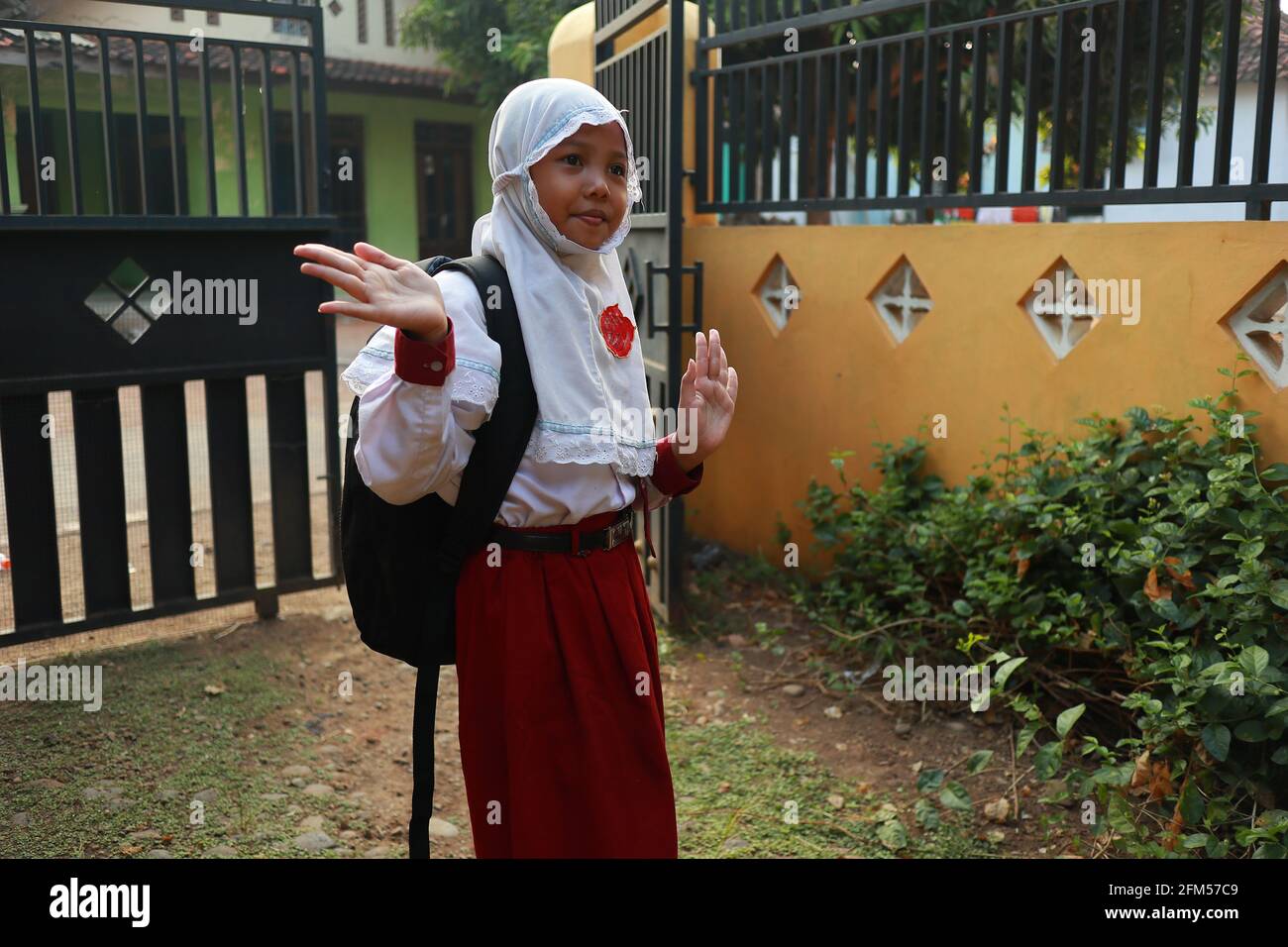 Una ragazza al livello della scuola elementare quando va a scuola, dalla sua casa fin dalla mattina e piena di entusiasmo Foto Stock