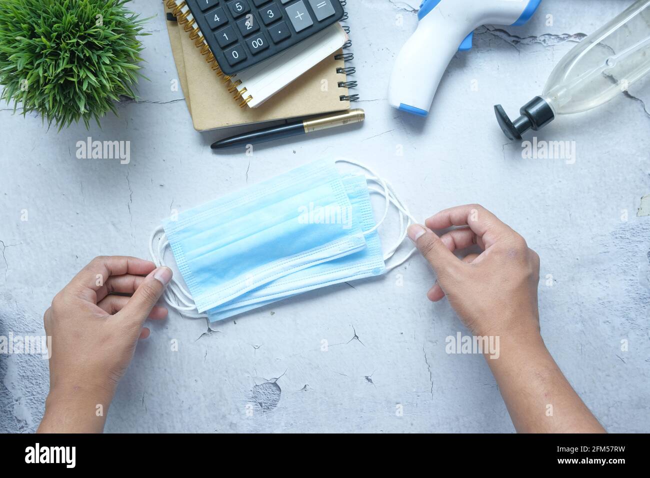 mano dell'uomo che tiene la maschera chirurgica del viso sul tavolo Foto Stock