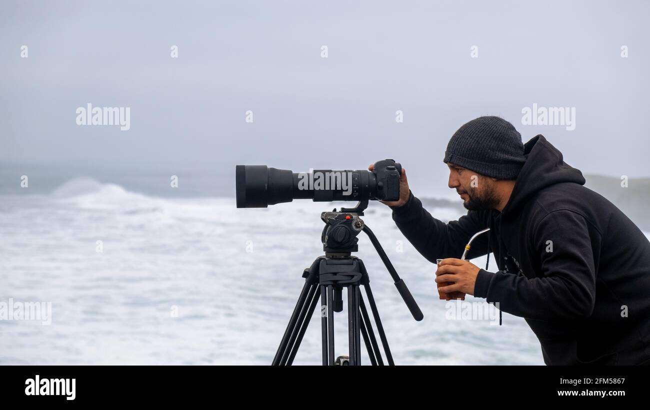 surf fotografo scattare foto del mare e surfisti su una giornata nuvolosa con la fotocamera e il teleobiettivo Foto Stock