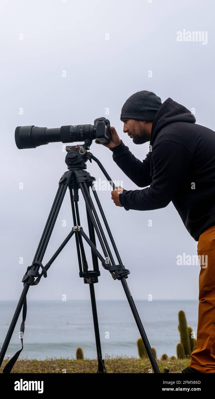 foto verticale di un fotografo della natura con la sua fotocamera e. Teleobiettivo per scattare foto di surf Cile Foto Stock