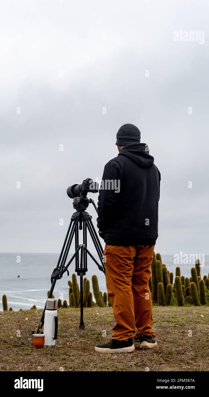 Surf fotografo in attesa delle onde con la sua macchina fotografica, thermos di acqua calda e compagno argentino Foto Stock