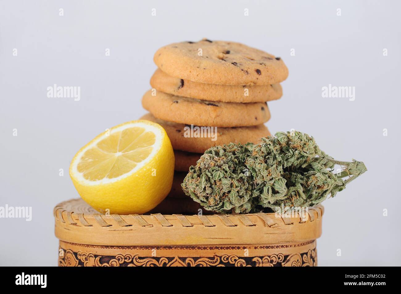 Dolci con olio CBD. Gemme di marijuana su sfondo bianco. Primo piano fiori di cannabis e biscotti al cioccolato. Foto Stock