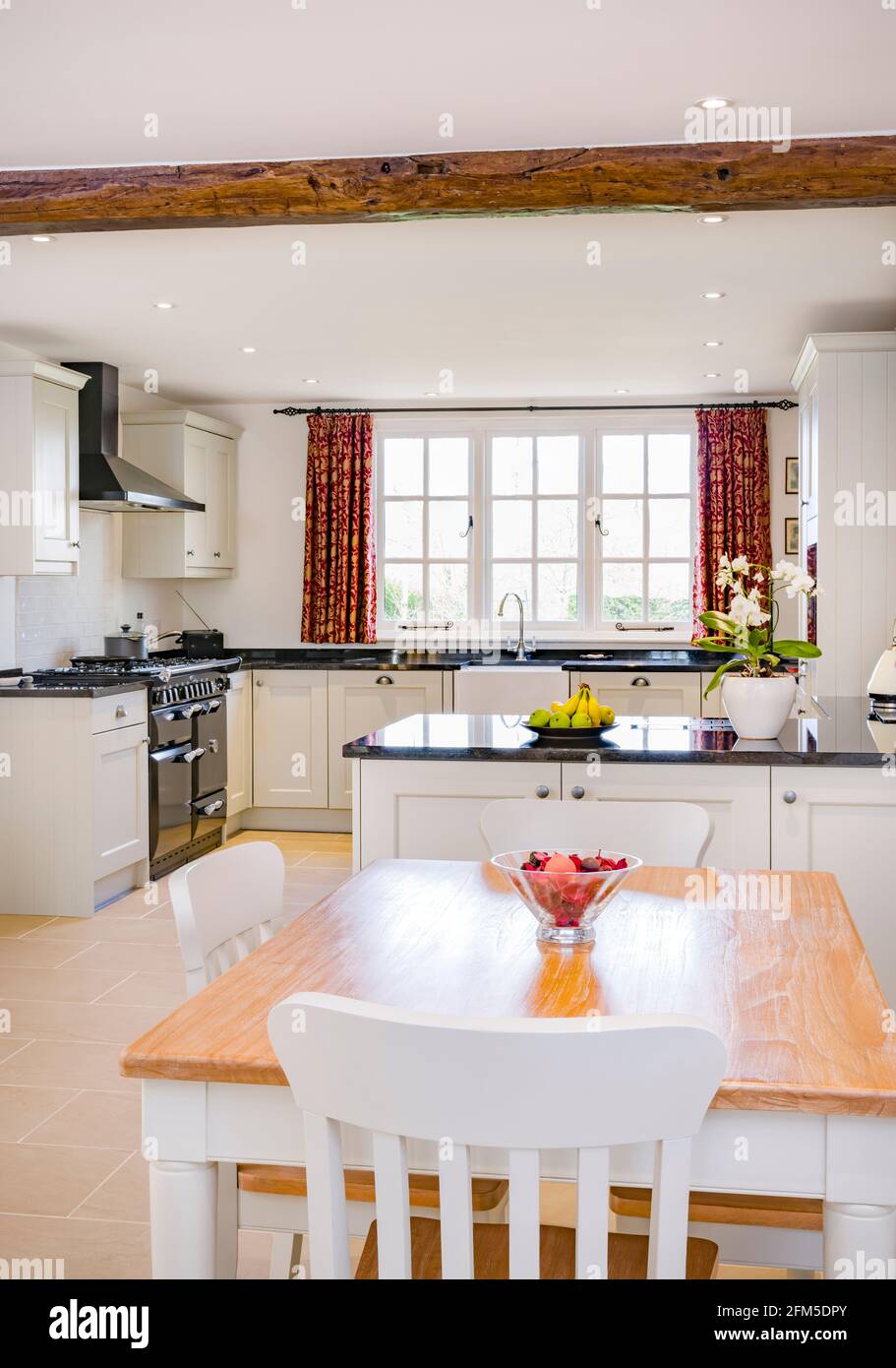 Arredamento cucina casa colonica design. UK open plan casa colonica cucina interna con moderni appartamenti in legno verniciato cucina, tavolo in legno per la colazione e sedie Foto Stock