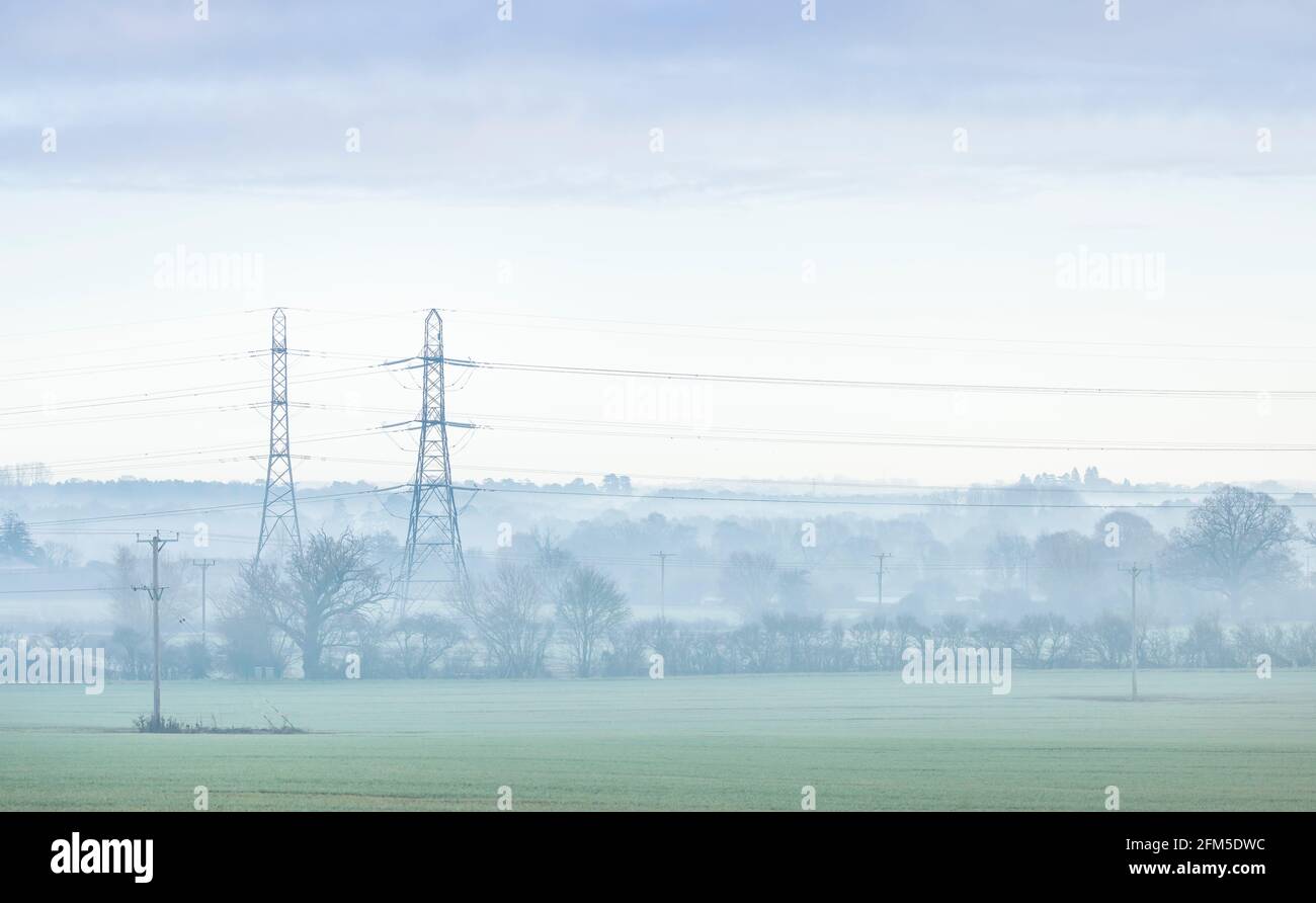 Tralicci elettrici in un paesaggio britannico in una mattina misteriosa. Aylesbury vale, Buckinghamshire, Regno Unito Foto Stock