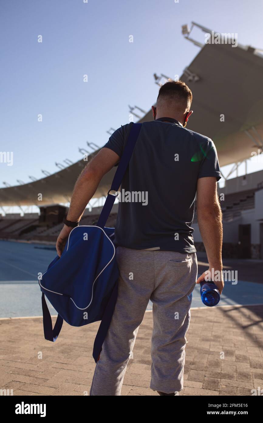 Vista posteriore dell'atleta maschio caucasico con gamba protesica in piedi sul campo sportivo Foto Stock