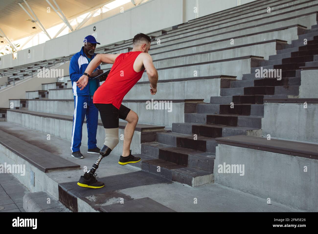 Atleta maschio caucasico con gamba protesica che sale sulle scale dello stadio Foto Stock