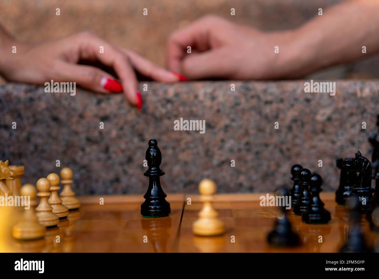 Scacchiera con figure in una giornata di sole nel parco con bokeh e sfondo sfocato da un paio di mani femminili e maschili Foto Stock