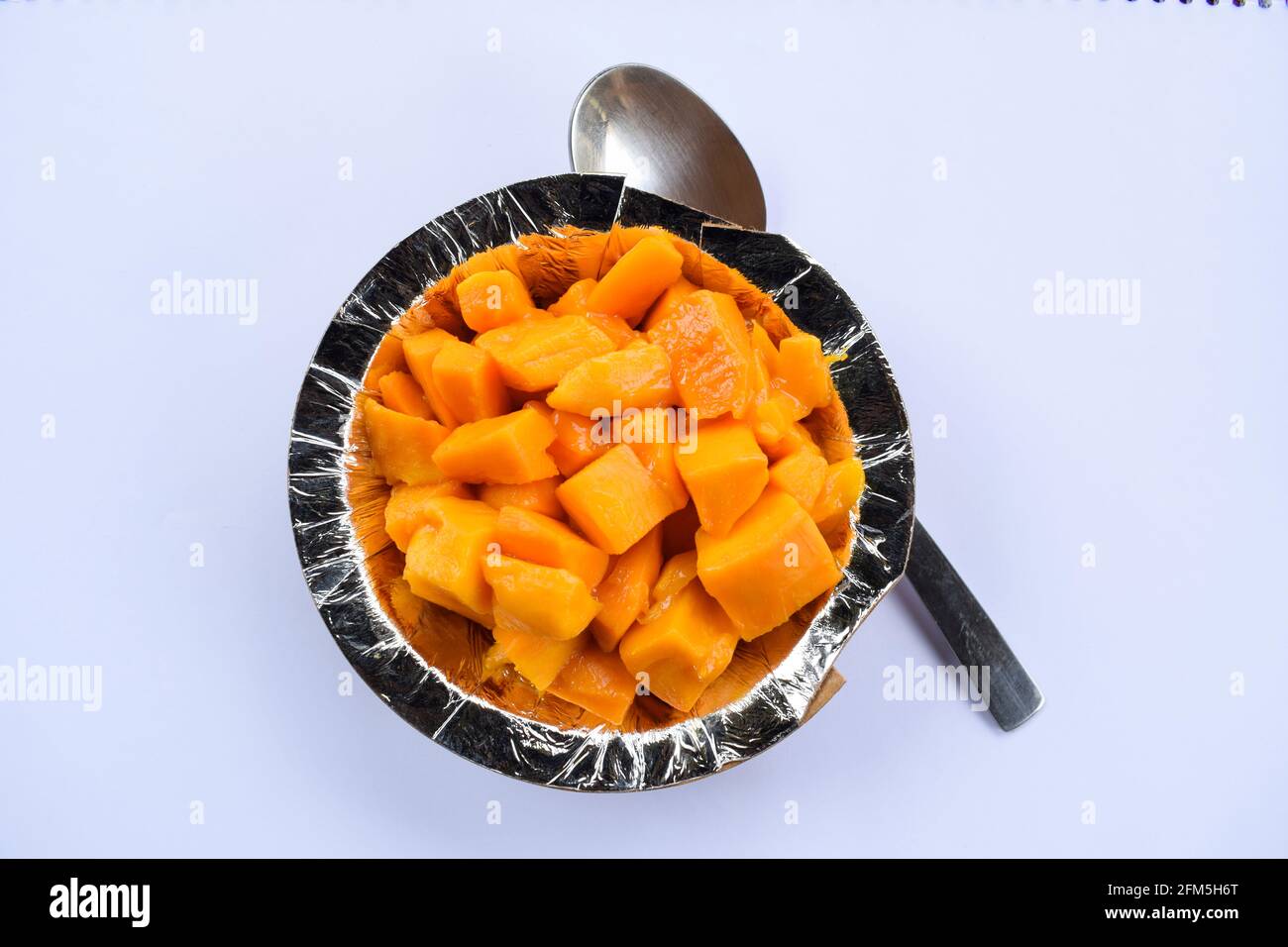 Tagliare i manghi serviti in ciotola o piatto su sfondo bianco. Indiano o pakistano asiatico frutta estiva mature mango pronto a mangiare Foto Stock