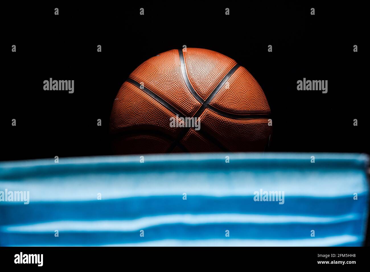 Palla da basket e maschera medica. Il concetto di misure di quarantena del coronavirus, di arresto della lega, di concorsi, di misure preventive. Foto Stock