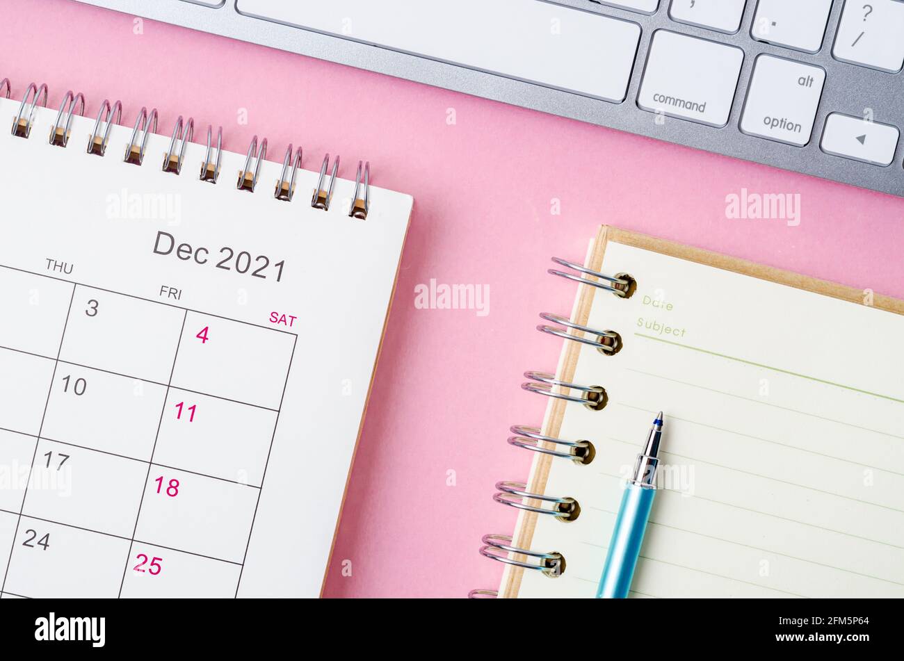 Calendario di dicembre 2021 con note book su sfondo rosa. Foto Stock