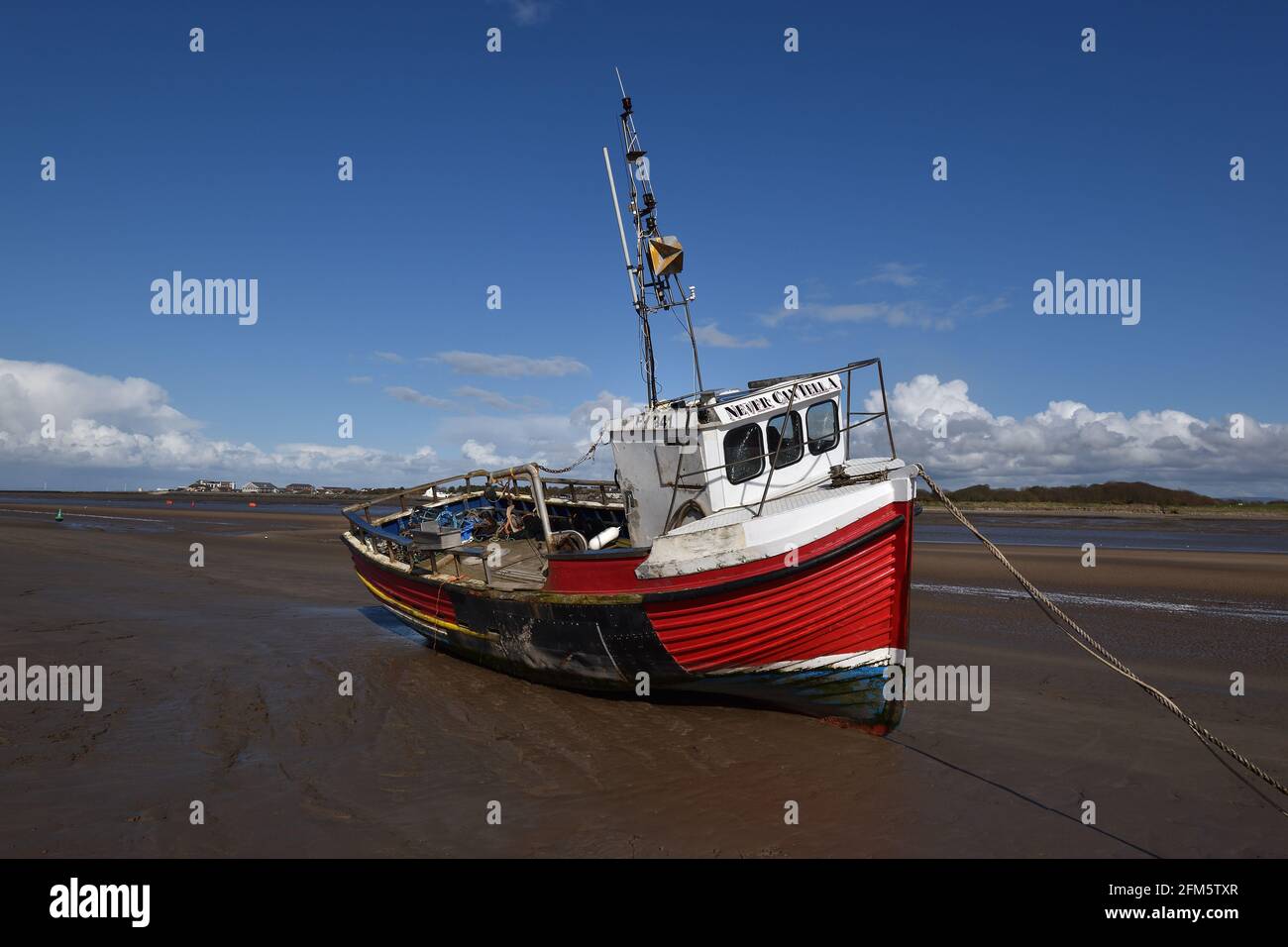 Barca rossa e bianca ormeggiata sulle pianure di fango del fiume Wyre, nome della barca 'Never Can Tell A' Foto Stock