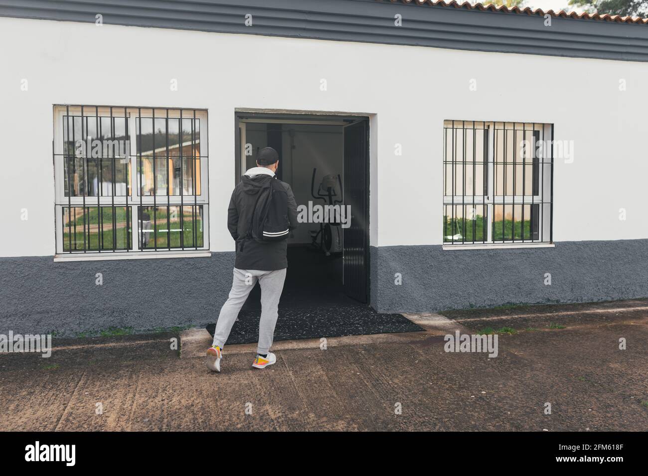 Uomo che arriva in palestra. Zaino e cappuccio. Foto Stock