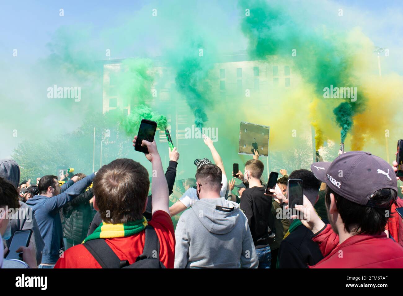 Protesta contro Glazer al campo di football Old Trafford. Tifosi che tengono telefono cellulare verde e oro fumo flare. Stadio Manchester United, Regno Unito. Foto Stock