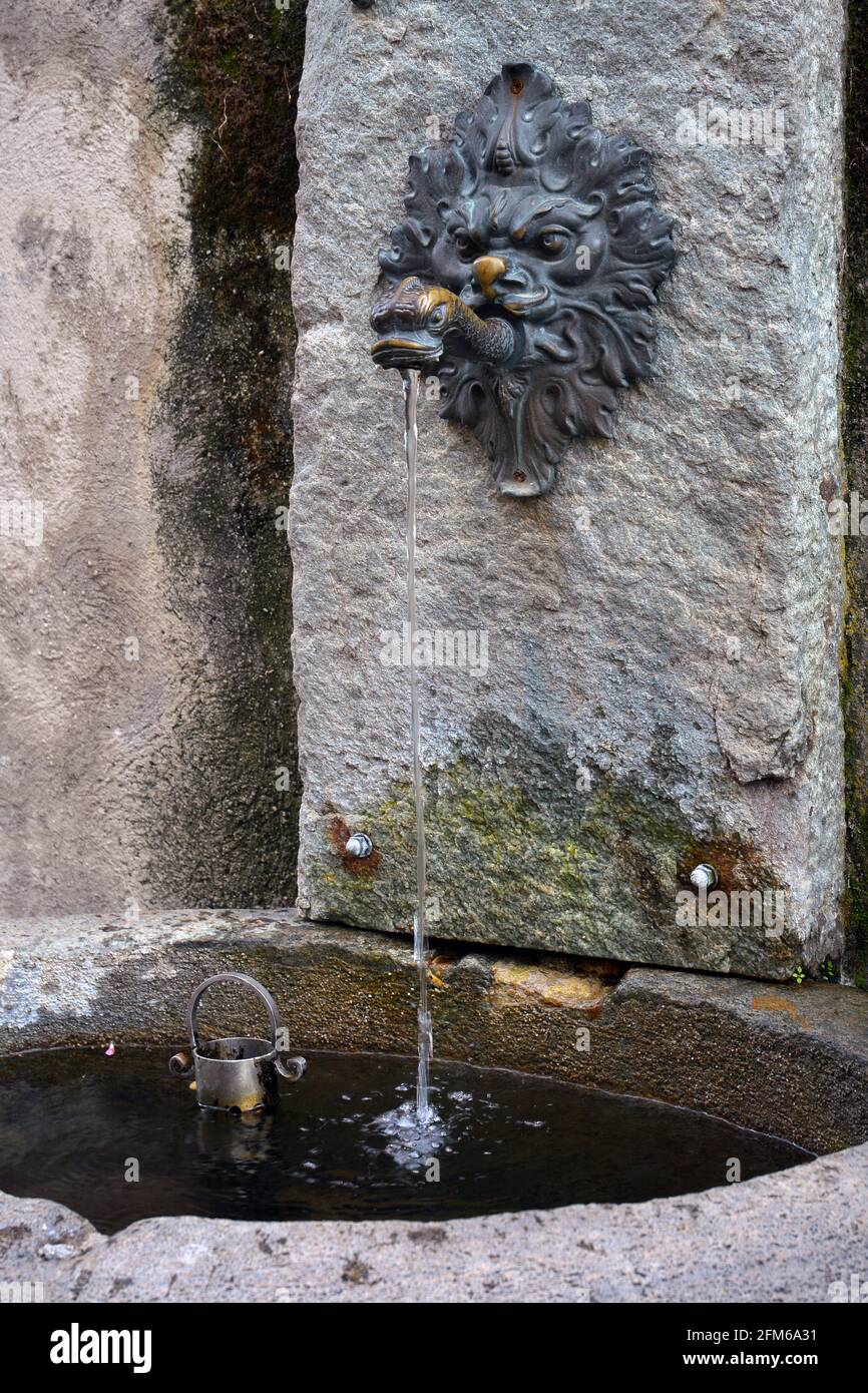 Antica fontana in pietra potabile di acqua fresca di montagna con leone e a forma di pesce Foto Stock