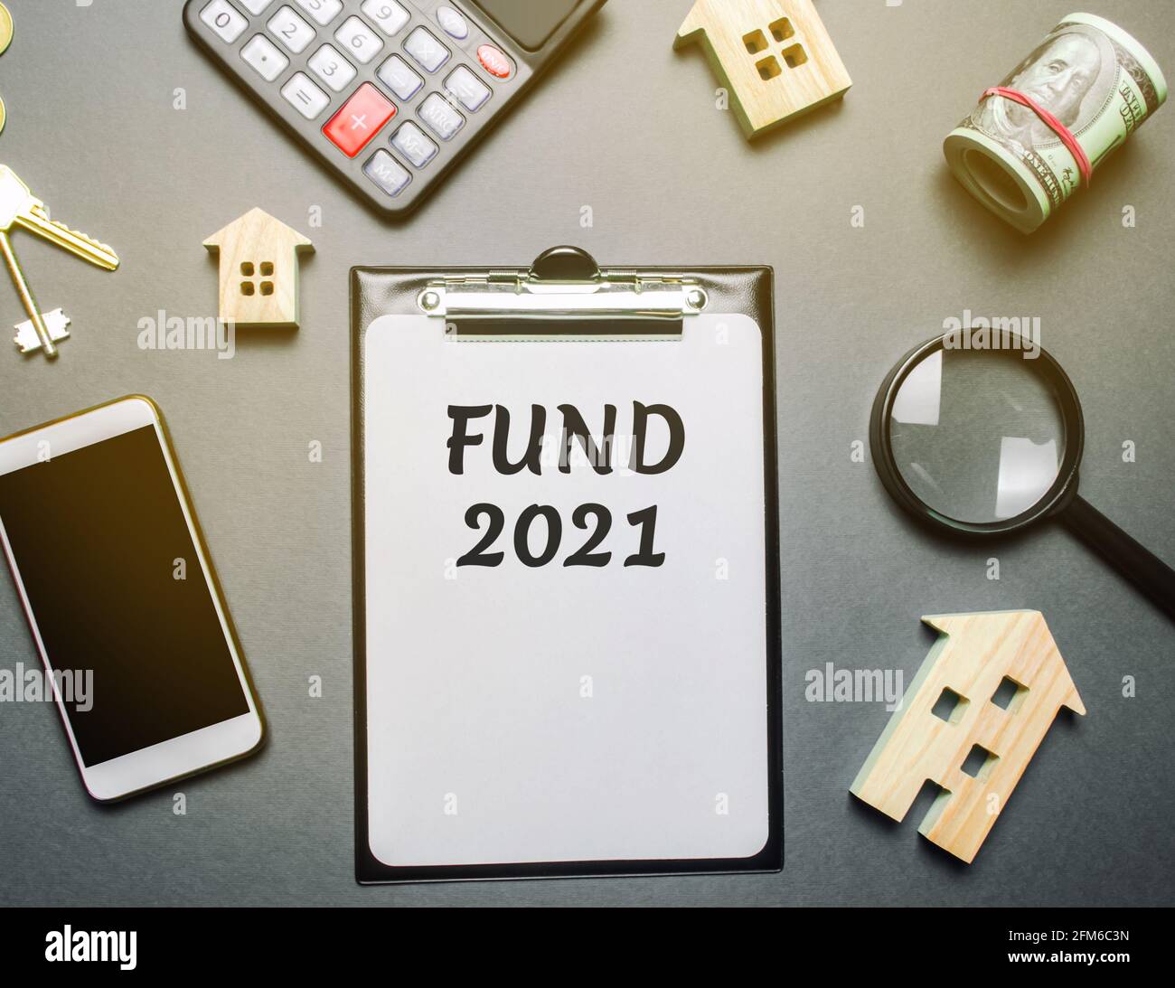 Note con le parole FONDO 2021, case di legno, denaro e telefono. Concetto di investimento immobiliare. Progetti, costruzione e funzionamento di immobili ob Foto Stock