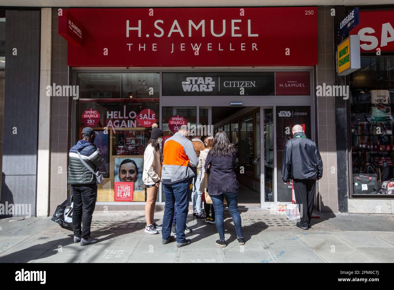 Code di acquirenti che aspettano fuori da una filiale di H. Samuel gioiellieri su Oxford Street, Londra, Inghilterra, Regno Unito Foto Stock