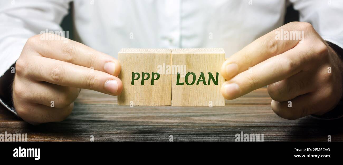 L'uomo d'affari mette i blocchi con le parole prestito di PPP - programma di protezione di paga. Prestito progettato per fornire un incentivo diretto affinchè le piccole imprese mantenga il th Foto Stock