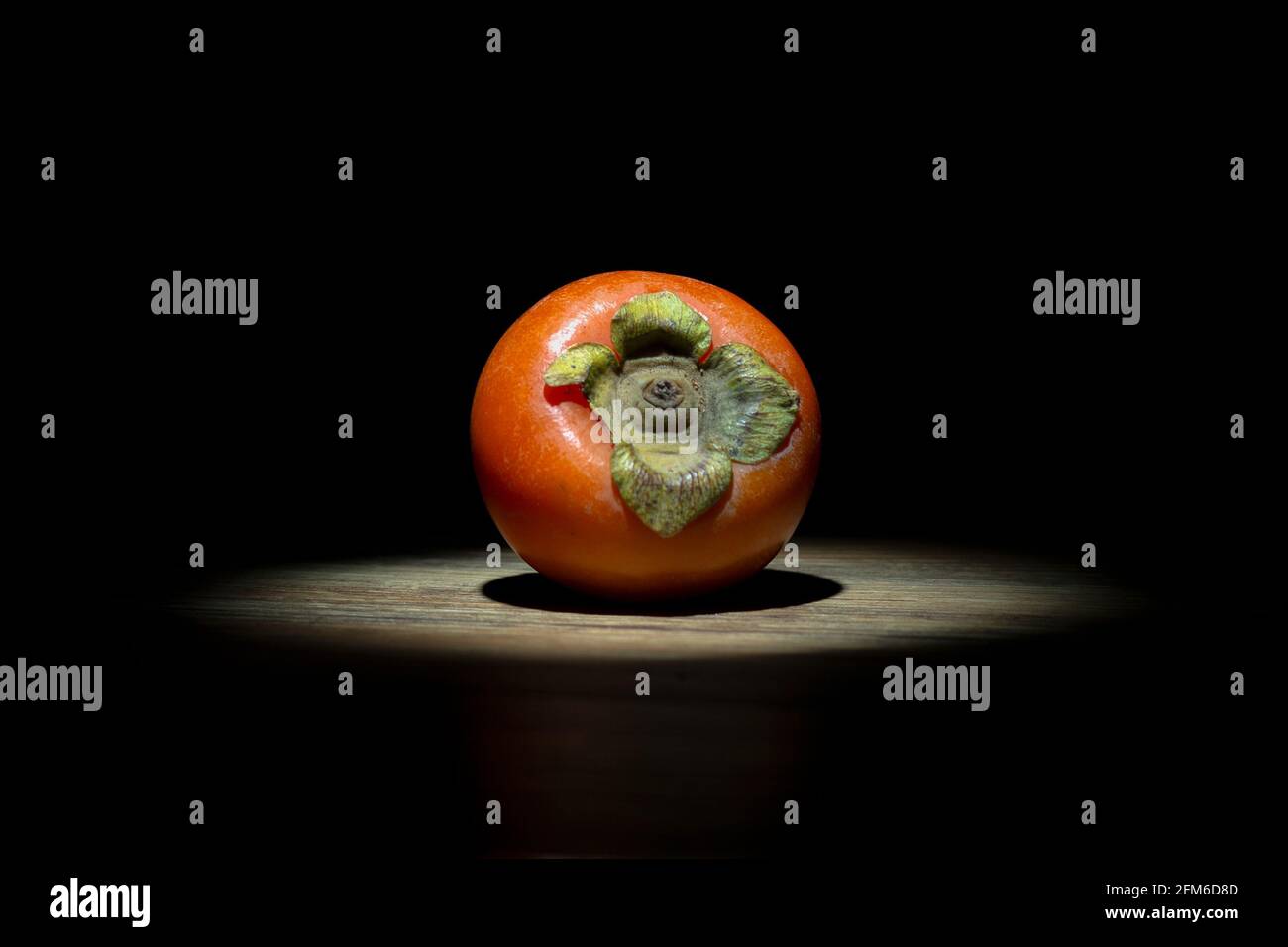 Un Persimmon acceso con un faretto Foto Stock