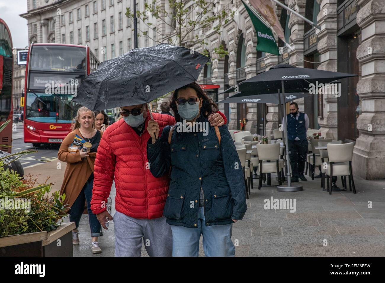 I turisti che camminano lungo Regent Street indossando maschere facciali in una giornata di primavera umida e ventosa mentre le restrizioni di blocco del coronavirus sono sollevate in tutto il Regno Unito. Foto Stock