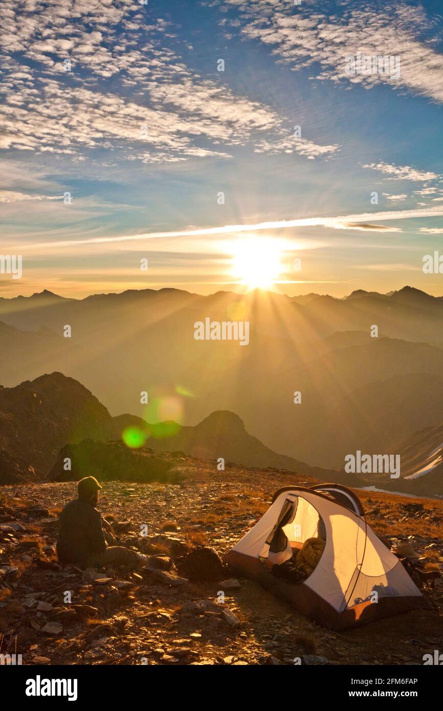 Un escursionista prende l'alba dal suo campeggio la cima di una montagna Foto Stock