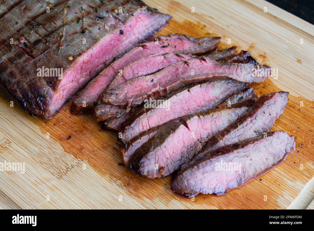 Bistecca di fiancate alla griglia marinata di Bourbon: Bistecca di fiancate medio-rare a fette su una tavola di bambù Foto Stock