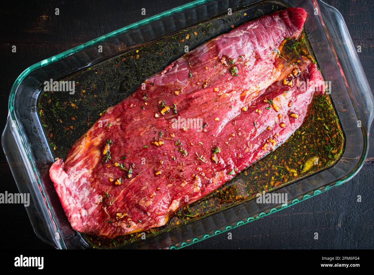Marinare la bistecca di fiancate in un piatto di vetro: Una bistecca cruda di fiancate marinare in una teglia di vetro Foto Stock
