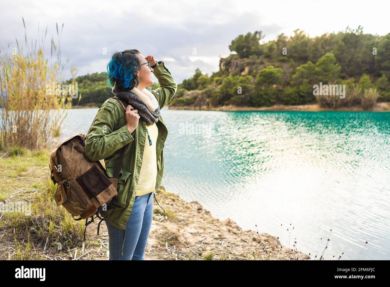 Viaggiatore femminile illuminato contemplando bellissimo lago all'alba Foto Stock