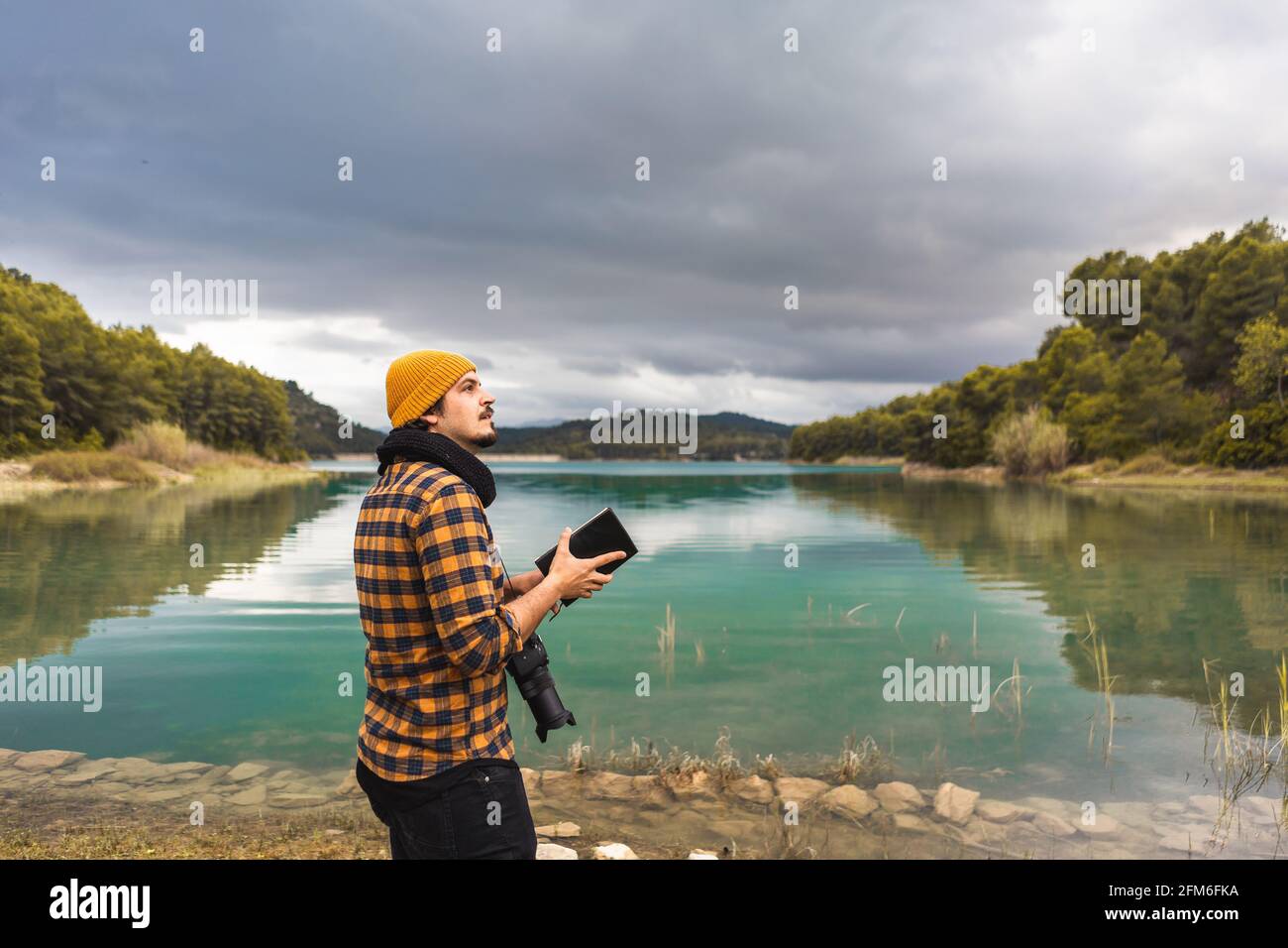 Guida turistica che branda la guida con cappello e macchina fotografica il lago Foto Stock