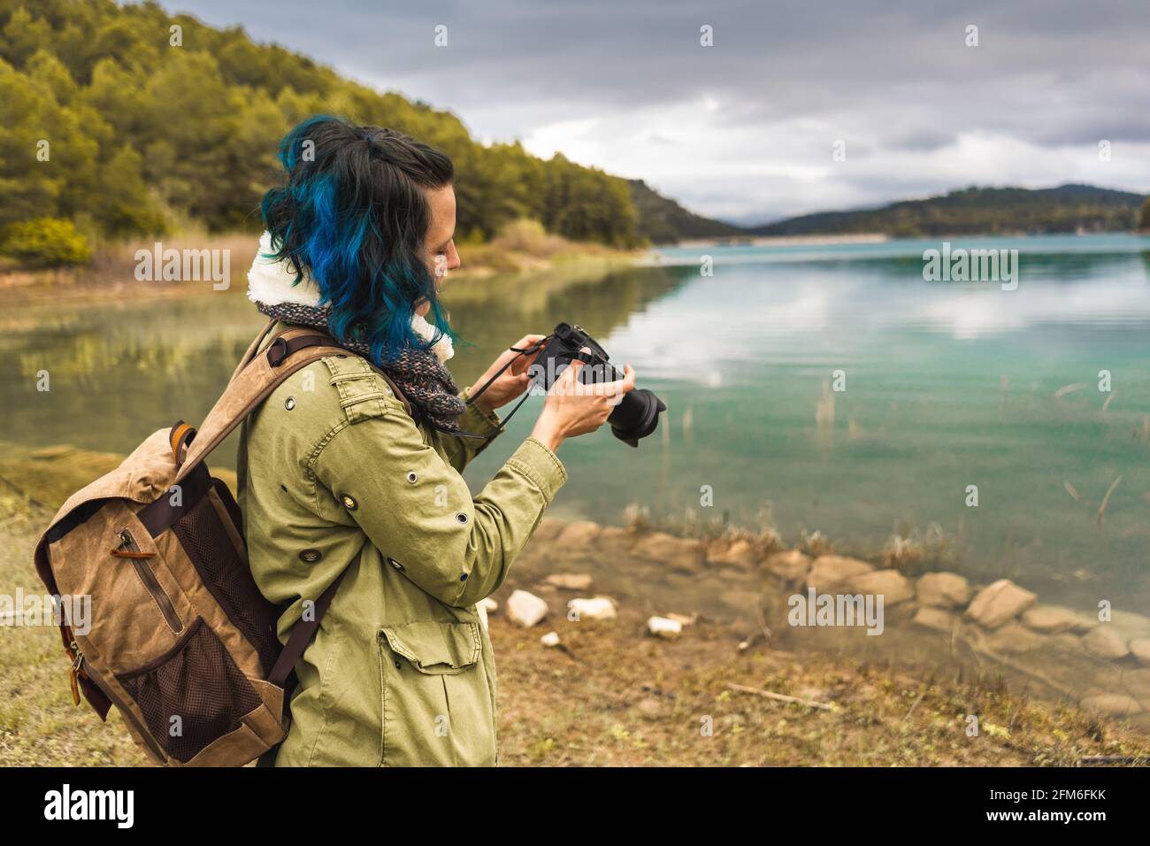 Turista con borsa in natura che scatta foto al lago Foto Stock