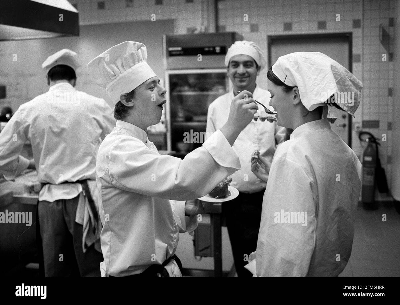 Uno studente di cucina, in una scuola di ristorante, che assaggerà il cibo di un altro chef. Foto Stock