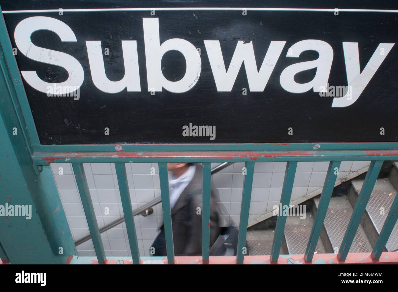 Un uomo decende le scale del sistema di transito di New York City conosciuto come la metropolitana. Foto Stock