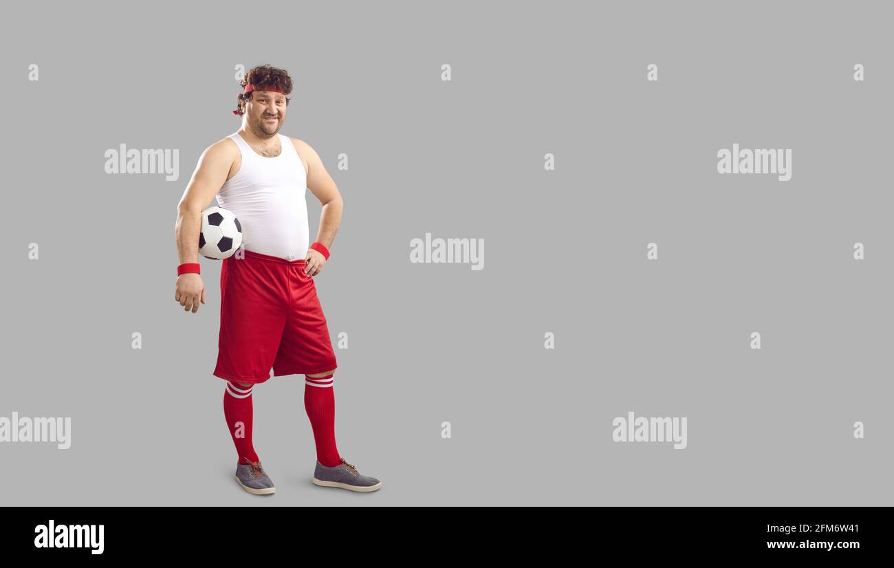 Felice giocatore di calcio chubby che tiene la palla e sorridendo in piedi copia sfondo spazio Foto Stock