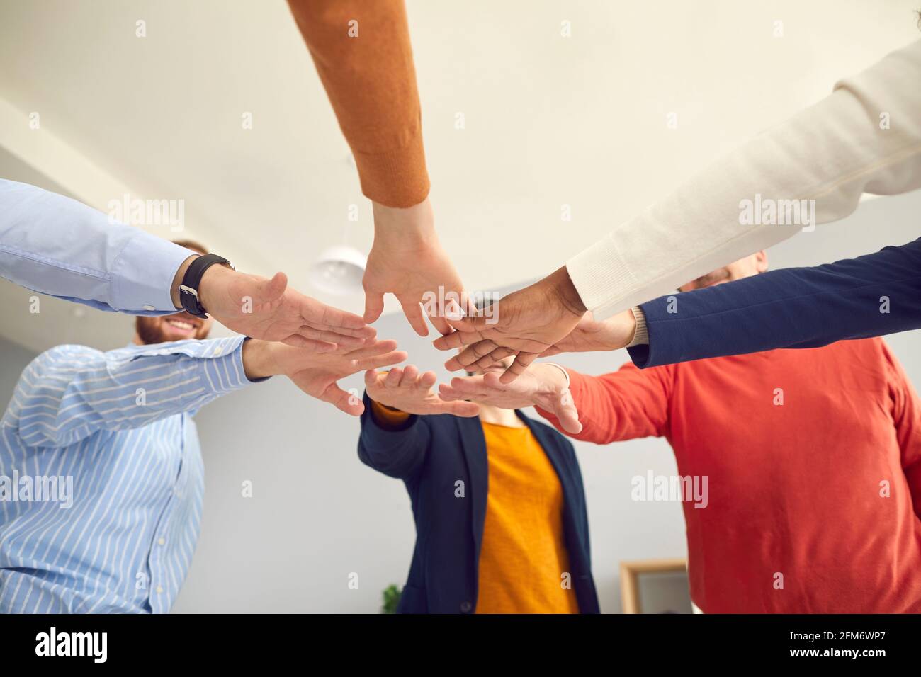 Foto di gruppo ad angolo basso di persone felici che lavorano in piedi cerchiare e unire le mani Foto Stock