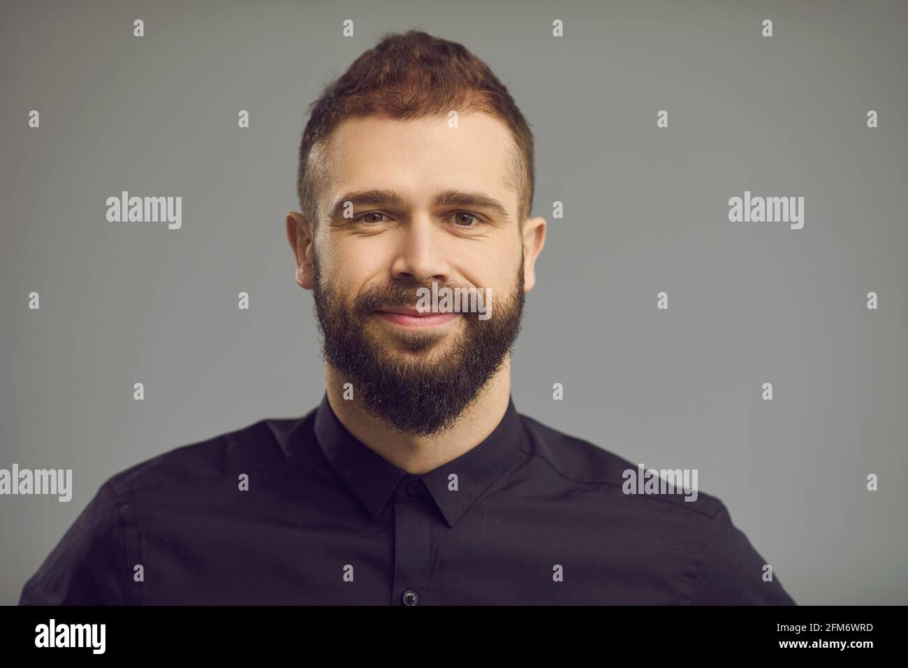 Bell'uomo bearded con sorriso sul volto headshot ritratto sopra sfondo grigio Foto Stock