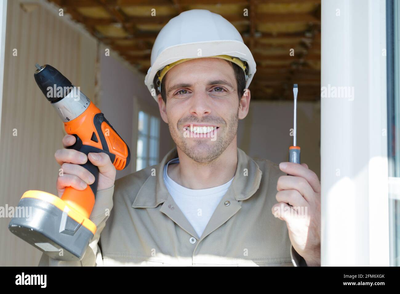 ritratto del costruttore che tiene cacciaviti elettrici e manuali Foto Stock