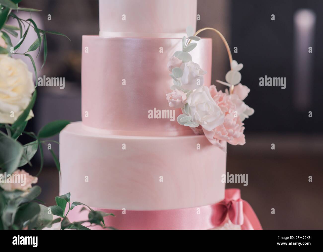 Primo piano di torta nuziale rosa a tre piani con fiori Foto Stock