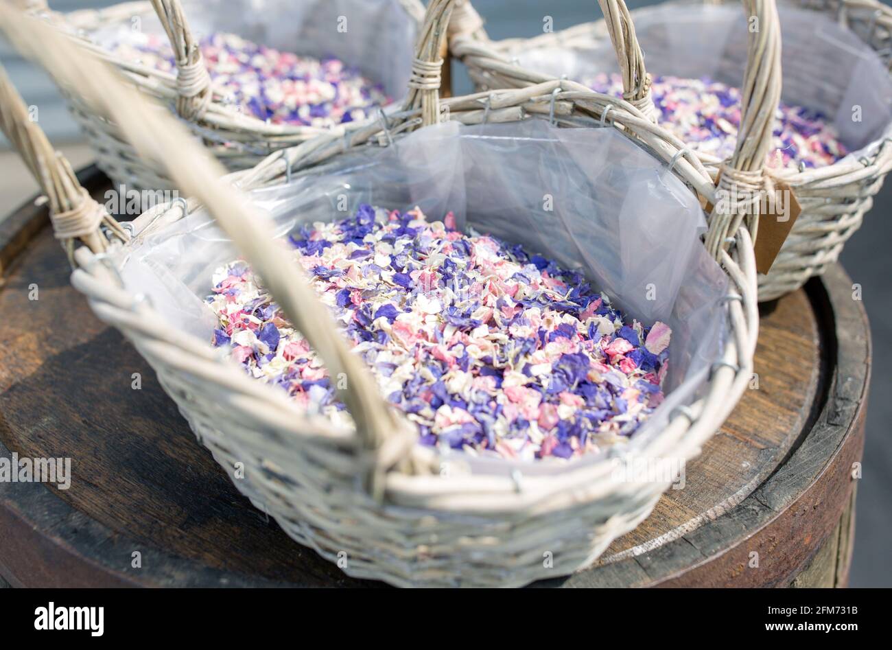 Cestini di confetti blu, rosa e bianco a un matrimonio su un barile Foto Stock