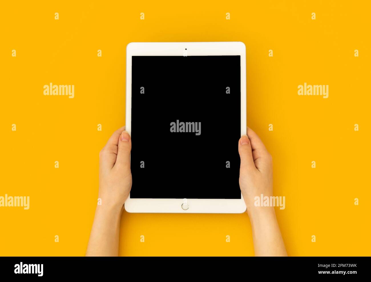 Kharkov, Ucraina - 5 maggio 2021: Tablet digitale Apple iPad in mano, schermo mockup su sfondo giallo, vista dall'alto Foto Stock