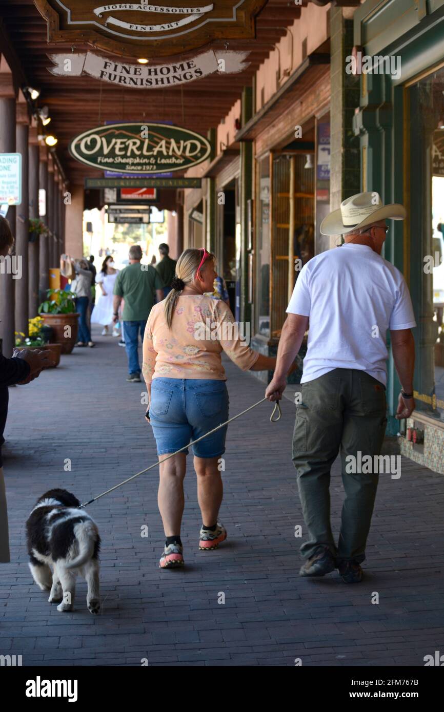Una coppia con un cane passeggiata lungo un marciapiede a Santa Fe, New Mexico. Foto Stock
